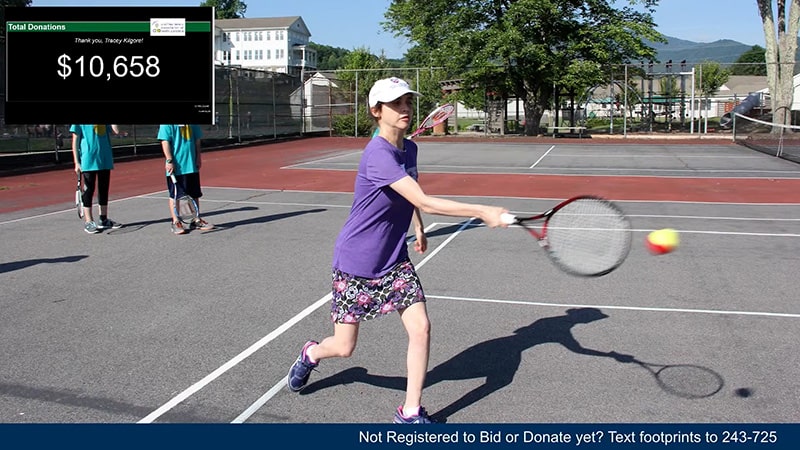 A young girl hitting a tennis ball.