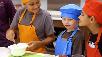 Three young boys cooking.